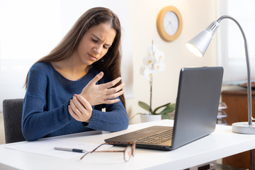 Teen girl with laptop computer at home complaining of wrist pain