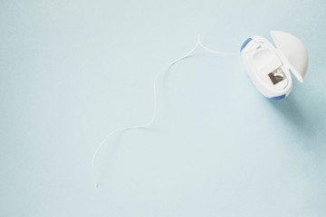 Dental floss on a blue background. Oral hygiene, teeth cleaning.