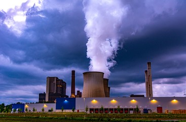 Coal Power plant in the sunset with smoke going out of a cooling tower.