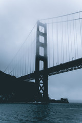 Moody photo of the Golden Gate Bridge from a Yacht. Foggy rainy day under the Golden Gate Bridge in San Francisco. Overcast weather and bad climate conditions.