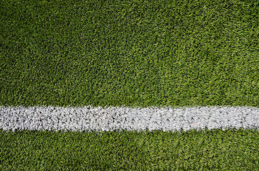 Artificial soccer grass field detail with white goal line.