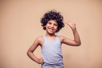 A portrait of smiling kid boy showing peace gesture. Children and emotions concept