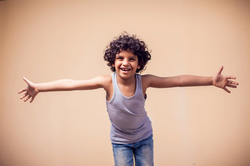 A portrait of smiling kid boy showing embrace gesture at camera. Children and emotions concept