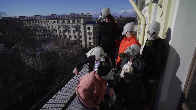 people in gas masks during a coronovirus epidemic walk their dog on the balcony