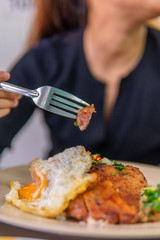 Vietnamese girl eating Com tam - a Vietnamese broken rice with pickles steak grilled pork ribs cucumber onion oil sweet chilies garlic fish sauce fried egg omelet Asian cuisine