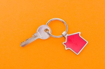 key chain with house symbol and keys on orange background,Real estate concept