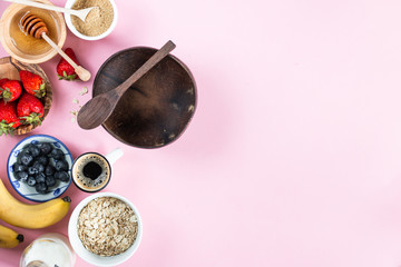 cereal and various delicious ingredients for breakfast on a pink background, top view copy space frame