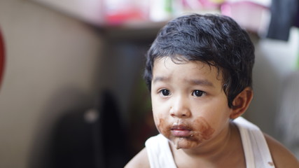 Little boy eating ice cream at home kid has dirty mouth with chocolate summer time concept. 