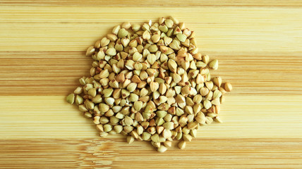 Green buckwheat seeds on a wooden background. Great food. healthy groats. Organic raw non-fried vegetarian food. The concept of a healthy, balanced and dietary diet. Copy space.