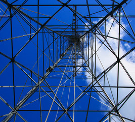 Texture energy pillars. Detail of electricity pylon against blue sky: high voltage electric pillar from below