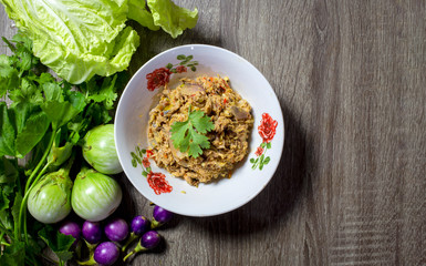 Top view of the Mackerel chili paste on a white plate with vegetables on a wooden table. Chili paste is a popular food for Thais with copy space.