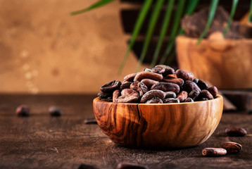 Unpeeled cocoa bean on wooden rustic background, close-up. Copy space