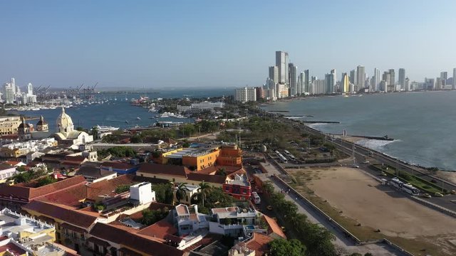 Old Town of Cartagena, Colombia - Drone shot rising from a street in the historical center of Cartagena de Indias revealing the Cathedral tower and the Skyline of Bocagrande in the background.