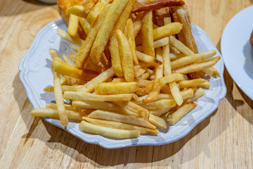 Golden French fries on white dish on the table.