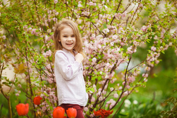 funny kid girl near with almond bush and tulips
