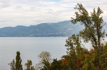 Fototapeta na wymiar Nature, mountains in the clouds and settlements around Lake Garda near the Sirmione town in Lombardy, northern Italy