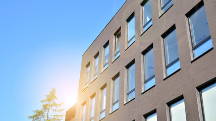 Glass building with blue sky background. Modern office building detail, glass surface clouds reflected in windows of modern office building.
