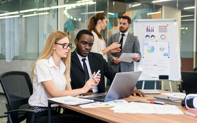 Professional male and female international business people in meeting room discussing joint project and reviewing business documents. Business teamwork concept.