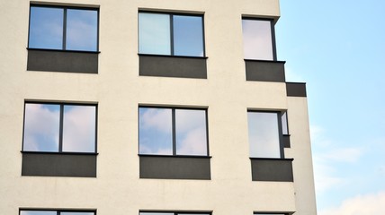 Glass building with blue sky background. Modern office building detail, glass surface clouds reflected in windows of modern office building.