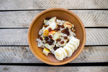 Oatmeal granola fruit porridge with banana, apples and raisins. Healthy sweet vegan breakfast. 
