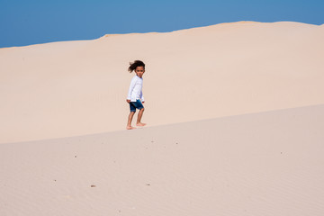 Fototapeta na wymiar Young boy walking on sand dune 