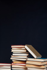 many stacks of educational books for college exams in the library on a black background
