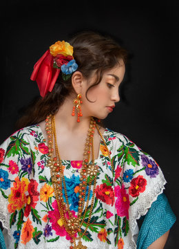 adolecente latina mexicanana, bailarina con traje tipico de yucatan mexico, con fondo negro, modelo de traje bordado con flores en punto de cruz hecho a mano, con cadenas de oro y cuentas de coral