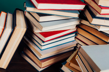 many stacks of educational books for exams at the university in the library on a green background