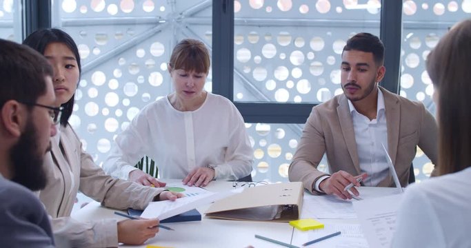 Brainstorming concept of male and female mixed-races team. Meeting of business partners. White-collars company workers. Men and women cooperating and discussing project and development.