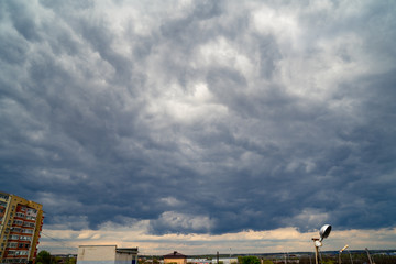 Fototapeta na wymiar dark grey cloudy sky with epic clouds above city. 