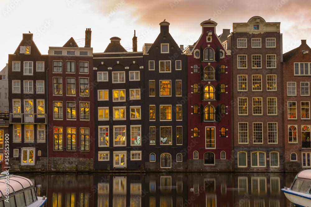 Wall mural Famous dancing houses and buildings in Amsterdam with reflection in canal water.