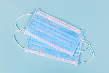 Two disposable medical face masks on blue background