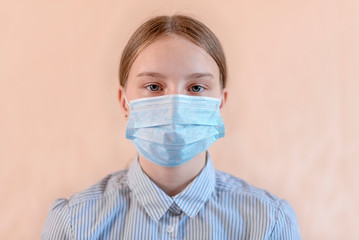 Close-up portrait beautiful teenager 12-15 years old, covers his face wearing medical blue mask, anti-coronavirus COVID-19 pandemic infectious disease outbreak protection, healthcare concept