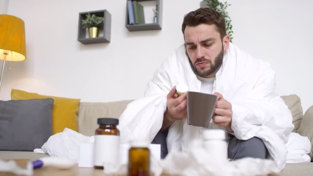 Tracking Of Sick Bearded Man Wrapped In Blanket Sitting On Couch And Taking Prescription Meds At Home