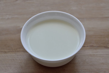 Obraz na płótnie Canvas White bowl with milk mousse on a wooden background