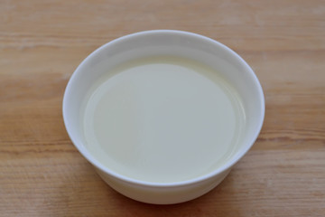 White bowl with milk mousse on a wooden background