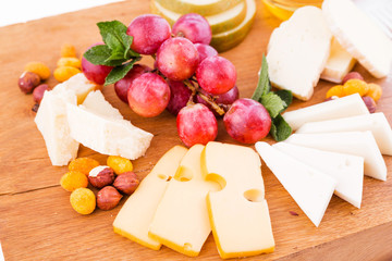 Cheese platter on a wooden board on a white background