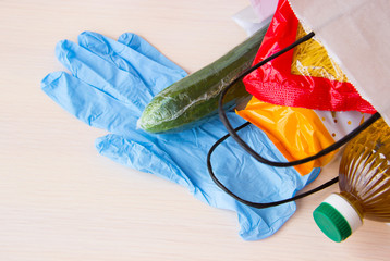 Paper bag with Food supplies crisis food stock for quarantine isolation period, copyspace. Pasta, cucumber, vegetable oil, medical gloves, package of cookies. Food delivery concept. Donation.