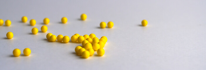 Round yellow vitamins are poured out on a white glossy table from a white plastic bottle. Concept. Place for the label. Diagnosis.
