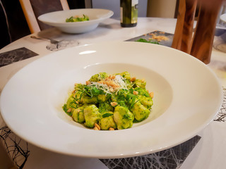 gnocchi with pesto on white plate with cheese