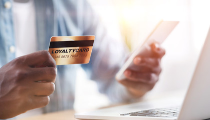 Collage with African American guy holding loyalty card while doing online shopping at home,...