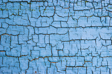 The texture of the old painted wall is covered with cracks and roughness close-up.