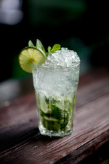 Cocktail with ice berries mint on bar counter daylight side view bokeh