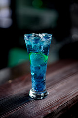 Cocktail with ice berries mint on bar counter daylight side view bokeh