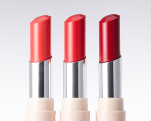 Close-up of the head of three red tone lipsticks.