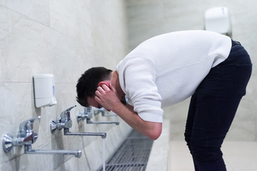 Muslim man taking ablution for prayer. Islamic Religious Rite Ceremony Of Ablution. Young Muslim man perform ablution (wudhu) before prayer.