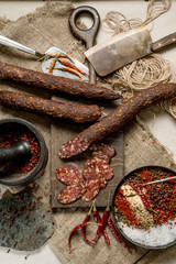 Beef jarky sausage with spices on wooden board with garlic pepper jar wooden texture top