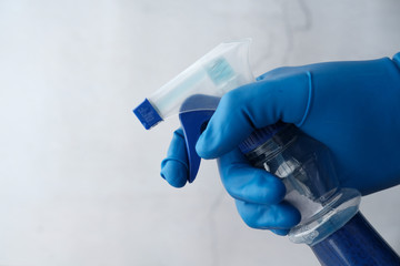 hand in blue rubber gloves holding spray bottle 