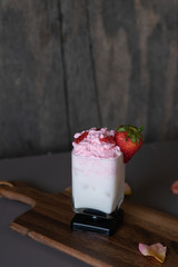 Strawberry Dalgona iced drink with fresh strawberries on a wooden background.
