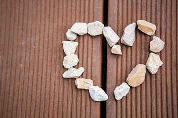 Herz aus Kieselsteinen auf dem Balkonholzboden gelegt